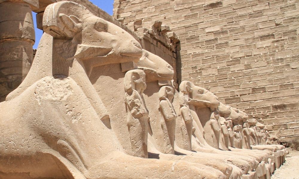 Ancient Egyptian hieroglyphics and relief carvings on the massive stone walls of the Karnak Temple Complex in Luxor.
