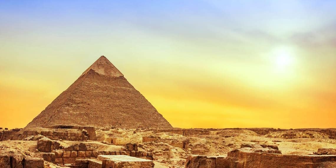 The Great Pyramid of Khufu at Giza illuminated by a golden sunset sky, showcasing the ancient limestone structure in Cairo, Egypt.