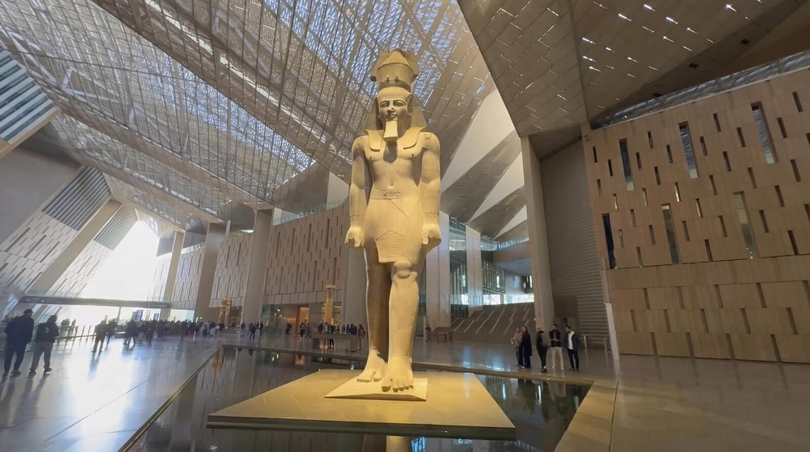 The colossal statue of King Ramses II standing in the grand atrium of the Grand Egyptian Museum (GEM) with modern architectural interior.