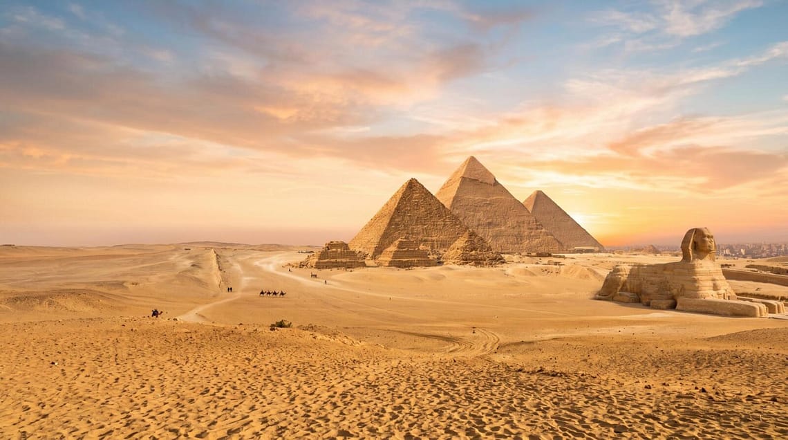 Panoramic view of the Great Pyramids of Giza and the Sphinx during a luxury sunset tour in Egypt.