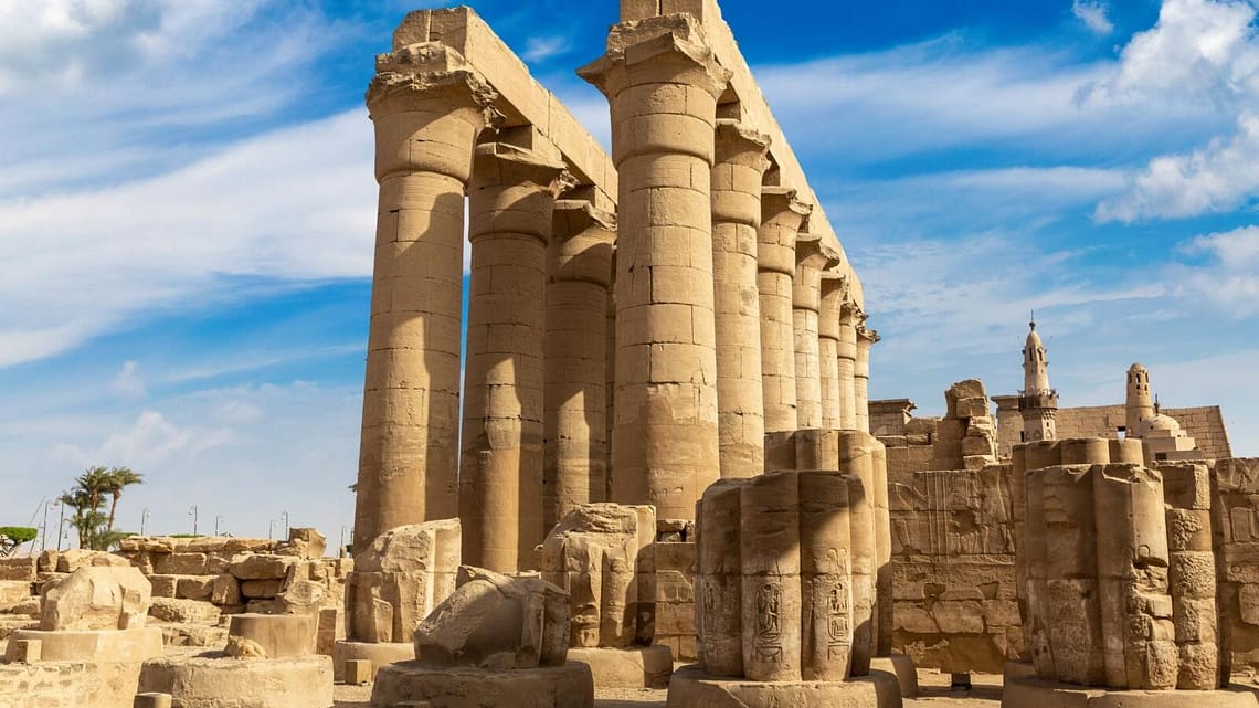 The massive papyrus-bundle columns of the Sun Court at Luxor Temple, showcasing ancient Egyptian architecture under a clear blue sky.