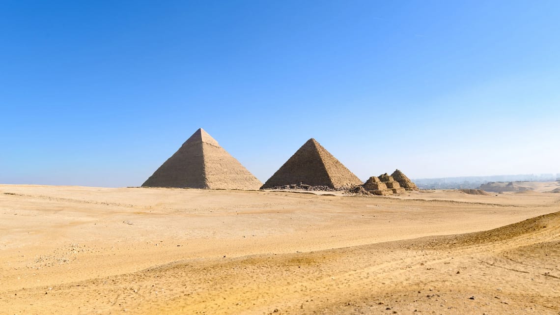 A wide-angle view of the Giza Pyramid complex under a bright blue sky, a primary destination for private day trips from Hurghada with Top Class Egypt Travel. - Cairo Day Trip from Hurghada