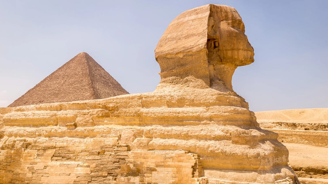 A side profile of the Great Sphinx of Giza with a pyramid in the background, visited during a private, expert-guided tour with Top Class Egypt Travel.