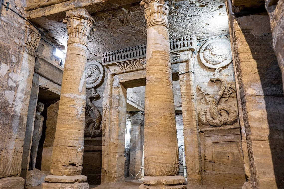 Underground stone pillars and carved reliefs inside the ancient Catacombs of Kom El Shoqafa in Alexandria, Egypt.