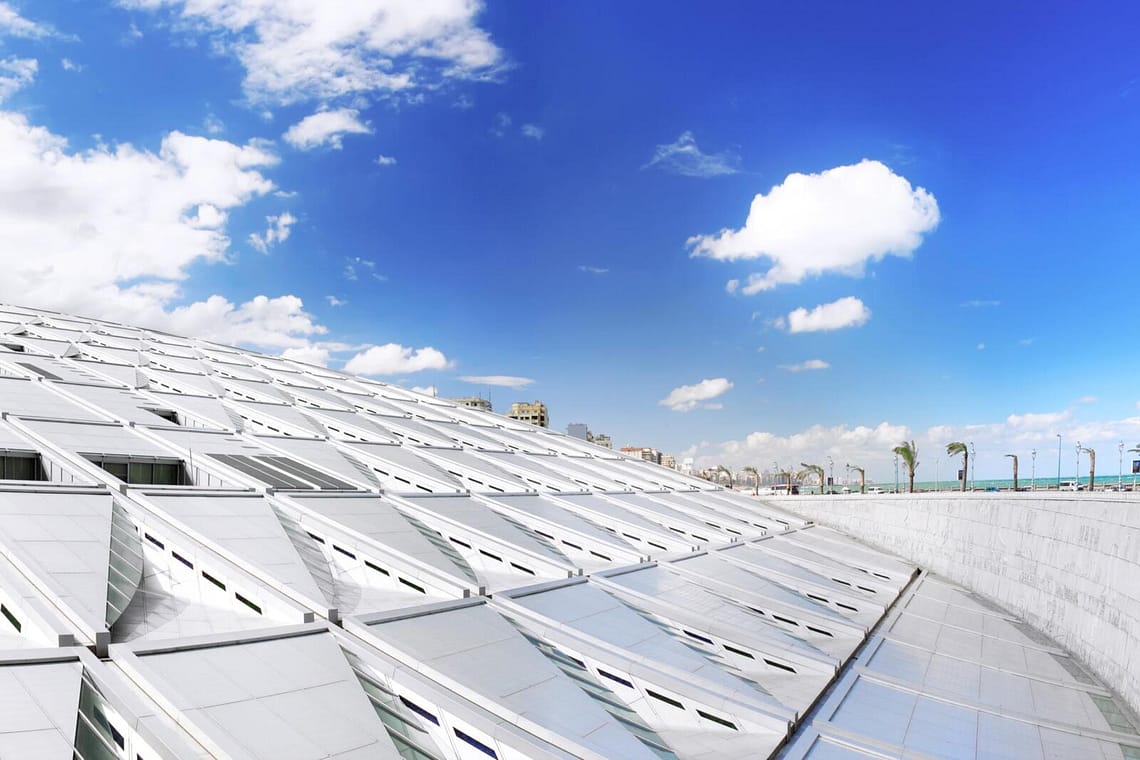 The modern architectural sun disk design of Bibliotheca Alexandrina library under a blue sky in Alexandria Egypt.