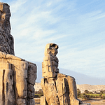 The two massive quartzite statues, the Colossi of Memnon, silhouetted against a golden-hour sky in Luxor, during an expert-guided private tour with Top Class Egypt Travel.