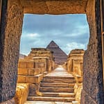 A view of the Great Pyramid of Giza framed by an ancient stone doorway, experienced during a private, custom-tailored tour with Top Class Egypt Travel.