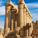 The massive papyrus-bundle columns of the Sun Court at Luxor Temple, showcasing ancient Egyptian architecture under a clear blue sky.