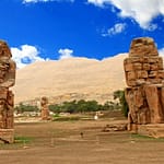 The two massive stone statues of Pharaoh Amenhotep III, known as the Colossi of Memnon, standing on the West Bank of Luxor, Egypt.