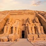 Colossal statues of Ramses II at the Abu Simbel temples carved into the sandstone cliff in Aswan Egypt at golden hour sunrise