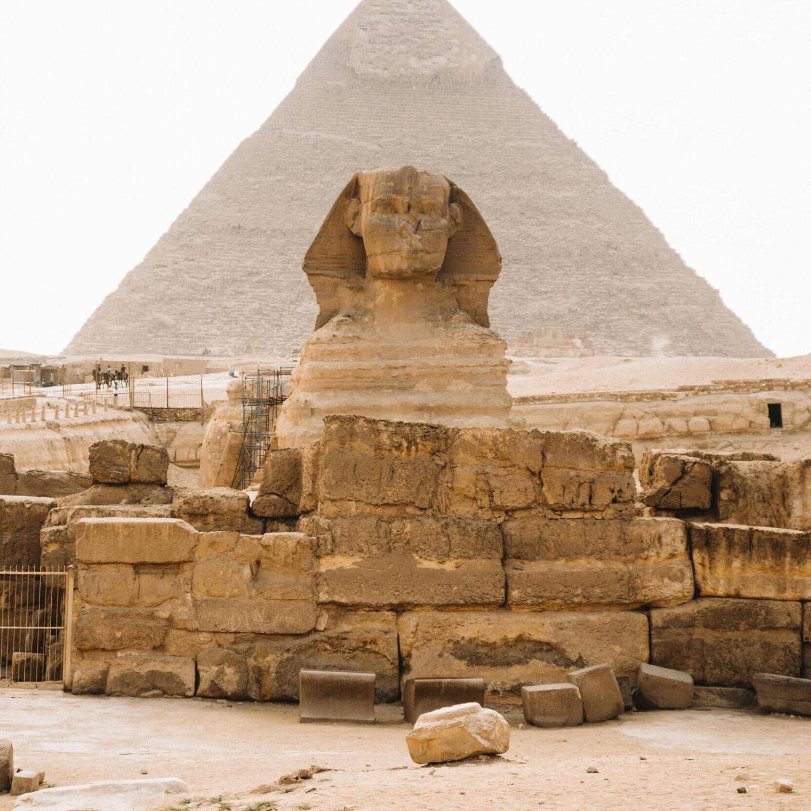 Frontal view of the Great Sphinx of Giza with the Pyramids in the background under a clear sky, Cairo, Egypt.