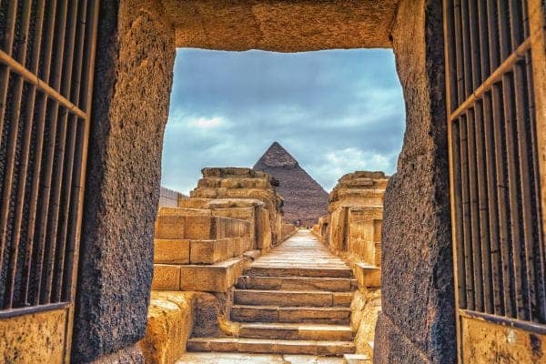 A view of the Great Pyramid of Giza framed by an ancient stone doorway, experienced during a private, custom-tailored tour with Top Class Egypt Travel.
