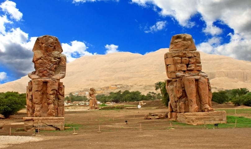The two massive stone statues of Pharaoh Amenhotep III, known as the Colossi of Memnon, standing on the West Bank of Luxor, Egypt.